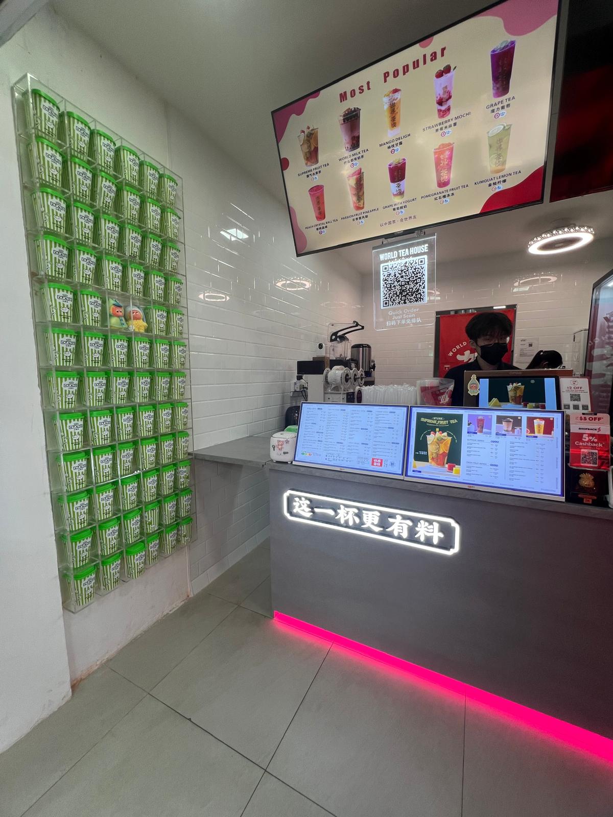 Side perspective of compact commercial kitchen layout featuring a green decorative wall display and overhead drink menus