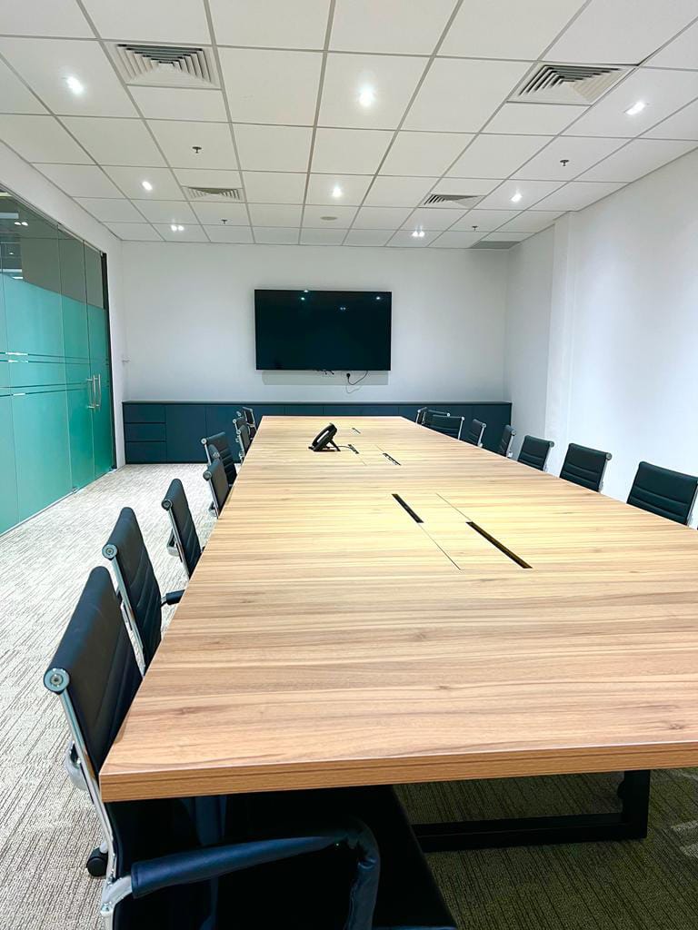 Long wooden conference table surrounded by executive mesh chairs in an acoustically partitioned meeting room