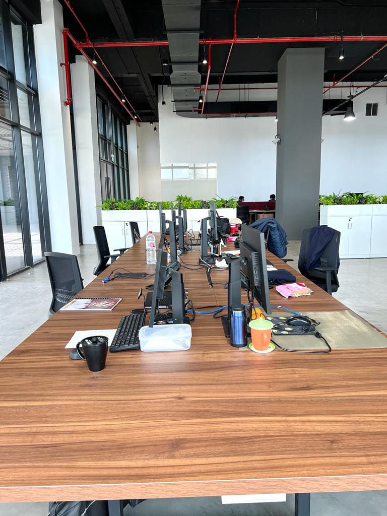 Industrial office desk arrangement with dark wood top, black metal frame, and exposed ceiling ductwork