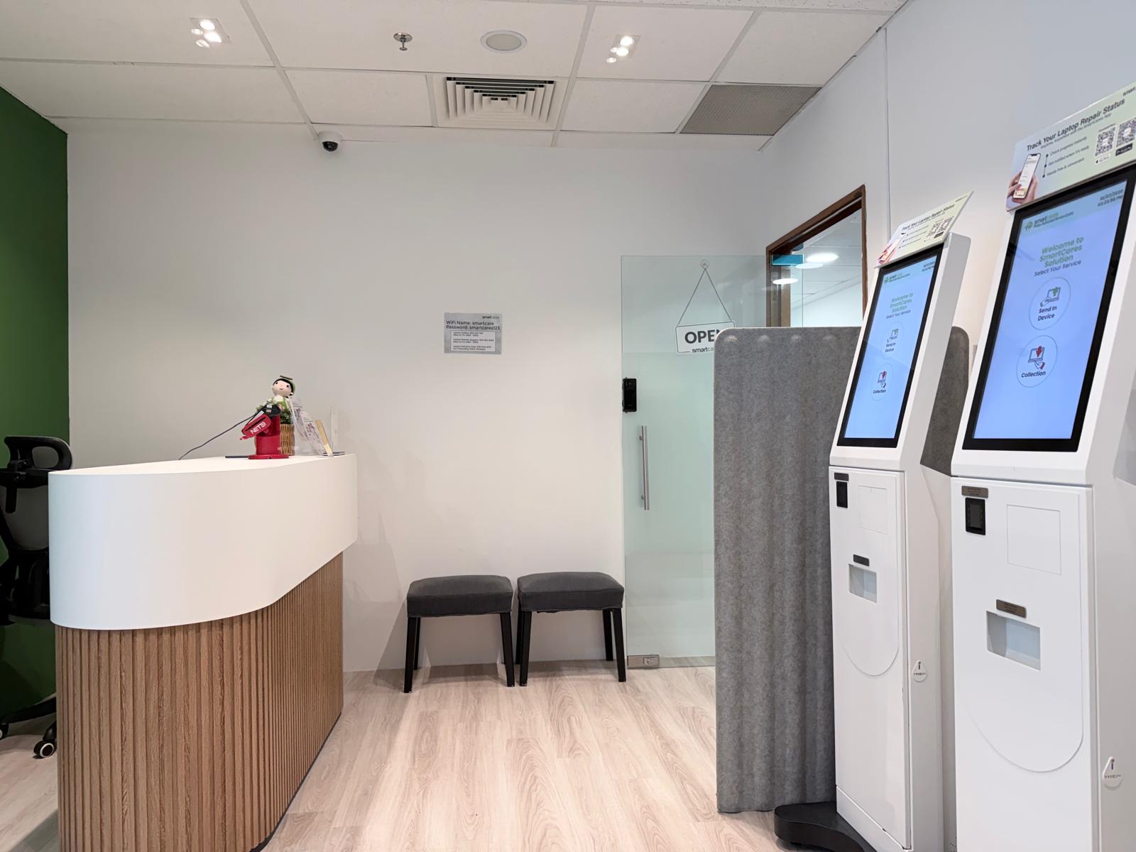 Front view of a custom rounded white reception counter opposite to automated self-service kiosks.