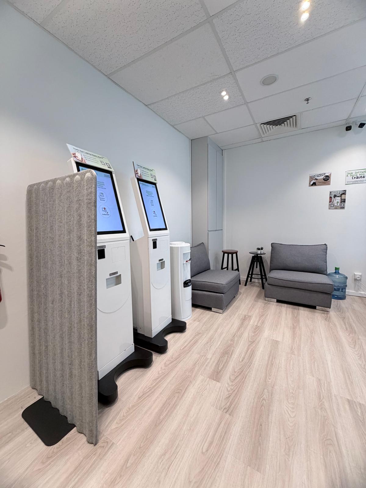Customer waiting area with gray lounge armchairs, grey privacy divider, and water dispenser.