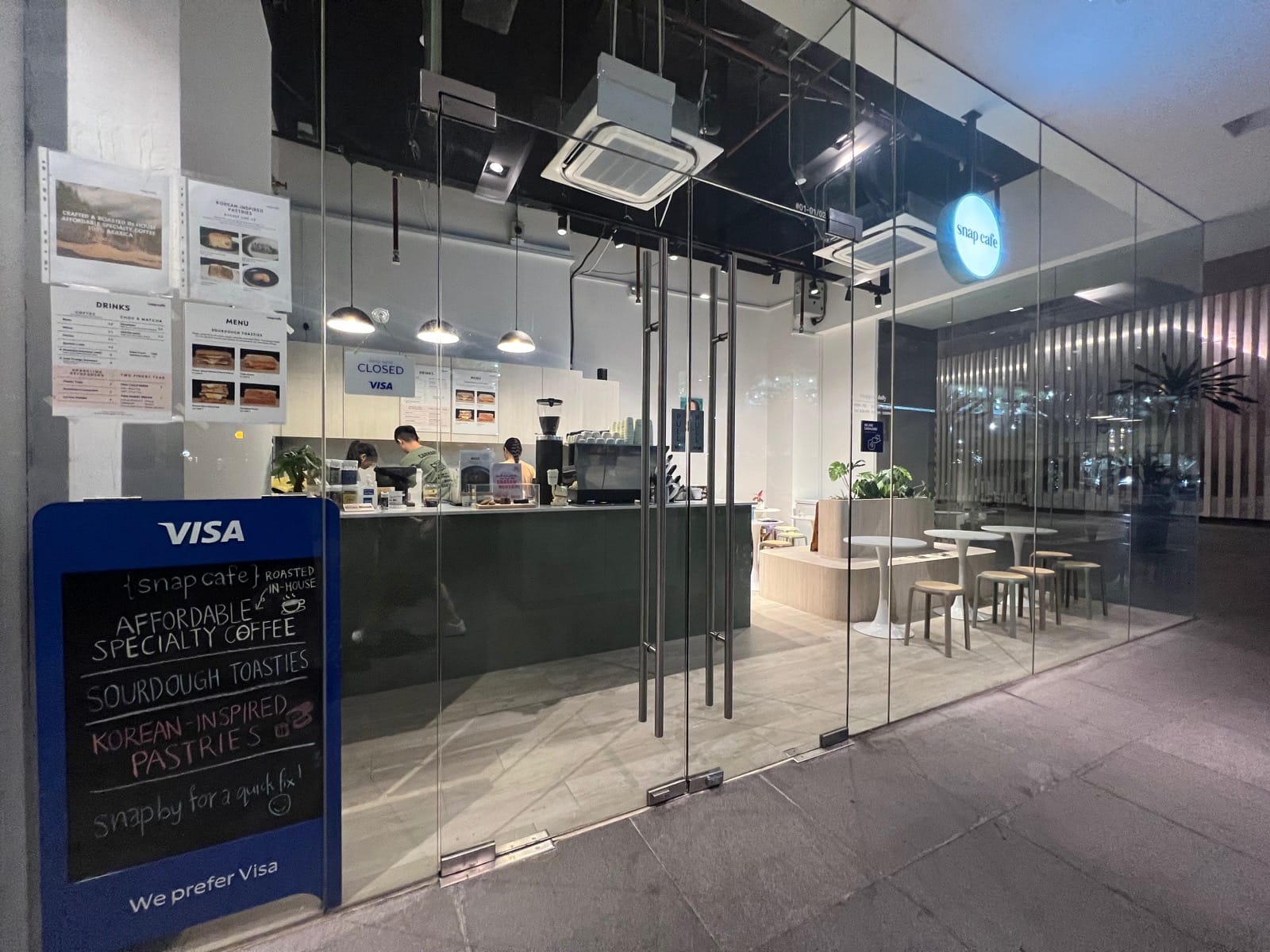 Modern glass storefront entrance and cafe interior constructed during an F&B renovation in Singapore