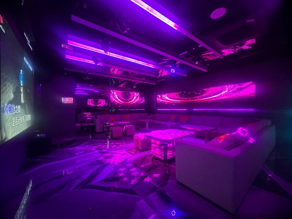 Private KTV room with purple ambient lighting and lounge seating.